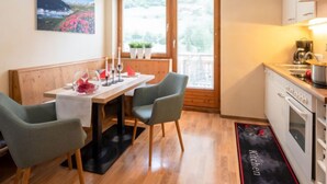 A compact kitchen with a dining area, wooden flooring, and a view of a mountain through the window. - Apartment Gams by Interhome (See)