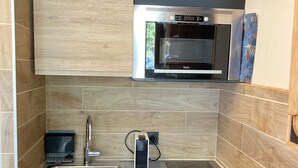A modern kitchen with a stainless steel sink, a built-in microwave, and a black induction cooktop. - Renovated 16m² studio, close to slopes, Avoriaz (Avoriaz)