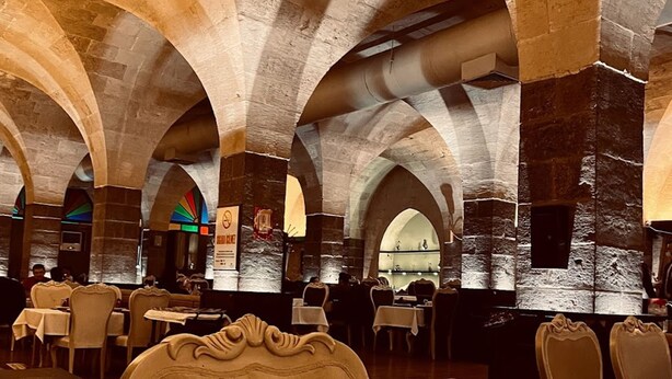 A restaurant with stone arches, tables, and chairs. - Bayazhan Butik Hotel (Gaziantep)