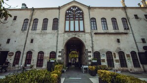 A historic building with a central arched entrance, multiple windows, and a sign indicating a pub. - Bayazhan Butik Hotel (Gaziantep)
