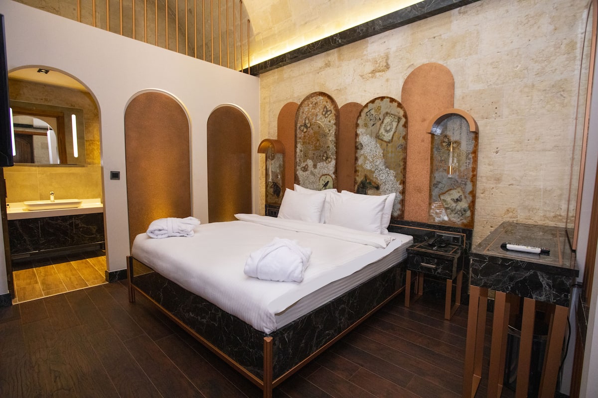 Ein Hotelzimmer mit einem großen Bett, einem integrierten Waschbecken und einem marmorbelagten Boden.