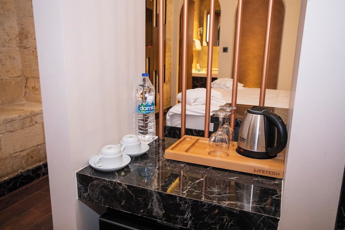 Een badkamermeubel in een hotelkamer met een waterfles, theeset en waterkoker.