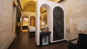 A hotel room with a bed, a minibar, a mirror, and a seating area. - Bayazhan Butik Hotel (Gaziantep)