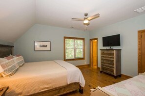 A bedroom with a bed, a dresser, a television, and a window. - Lakefront 3BR w/ Private Dock + Firepit | Free Tix (Mill Spring)