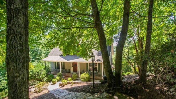 A house surrounded by trees with a stone pathway leading to the front door. - Lake Adger Home with Private Dock & Kayaks (Mill Spring)