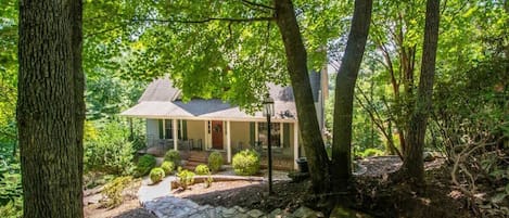 A house surrounded by trees with a stone pathway leading to the front door.