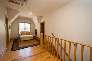 Ein geräumiges Zimmer mit einer Holztreppe, einem Sofa und einem großen Fenster.