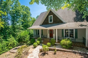 A house with a gabled roof, a front porch, and a stone pathway leading to the entrance.
