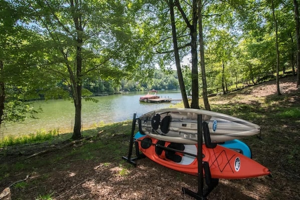 A kayak and canoe on a dock by a calm lake surrounded by trees.