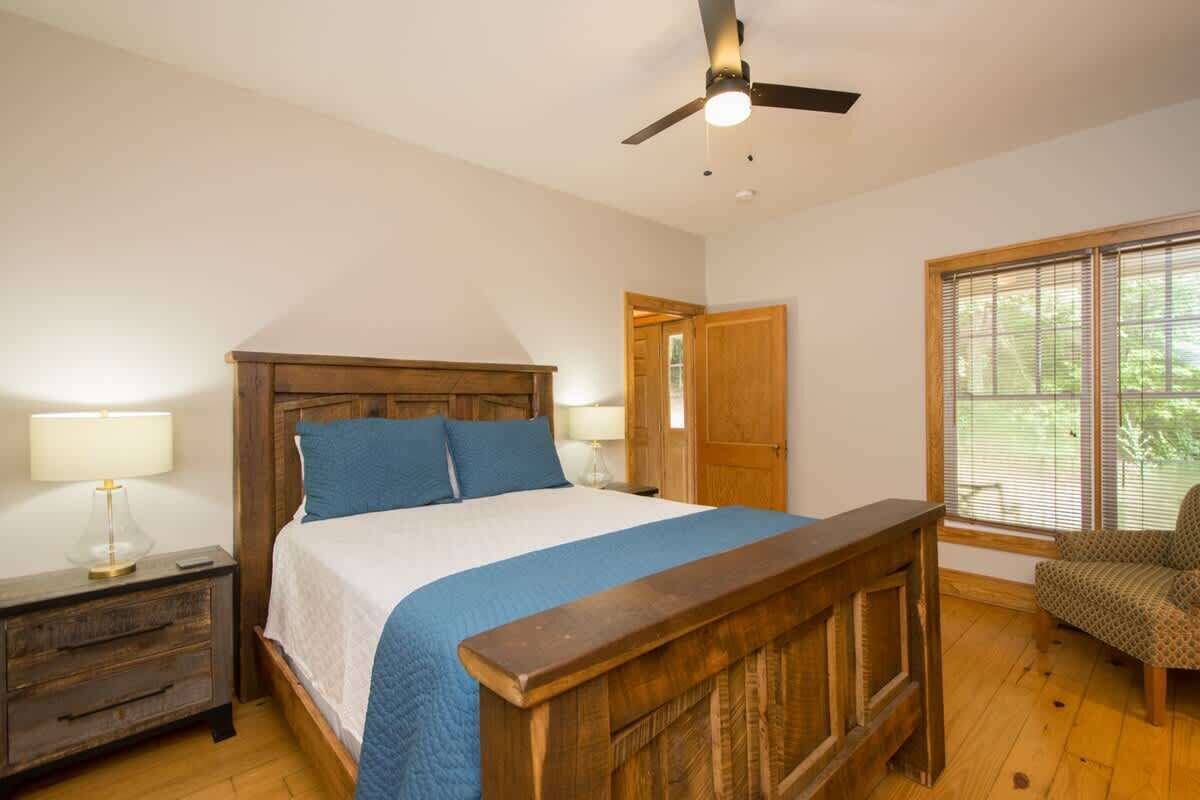 Un dormitorio con una cama de madera, una mesita de noche, una silla y una ventana con persianas.
