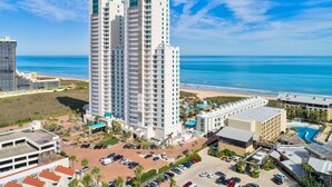 Un hotel de gran altura con varios balcones, piscina y vista a la playa.
