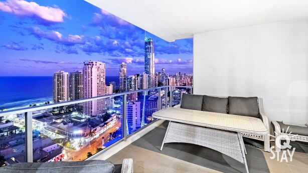 A balcony with a cityscape view, a white sofa, and a small table.