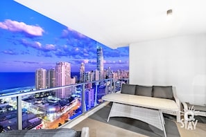Relax on the balcony with a panoramic city view, featuring a wicker sofa and small table.