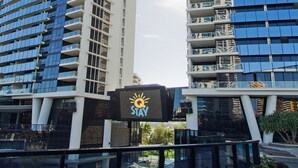 A modern hotel with a 'Stay' sign, featuring a glass facade and multiple balconies.