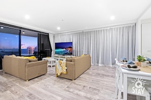 Relax in this stylish living room with a large flat-screen TV, comfortable sofa, and dining table.
