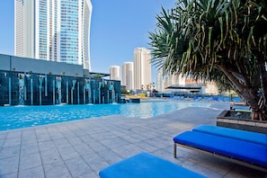 Relax by the pool surrounded by a deck and lounge chairs, with a seating area and palm trees nearby.
