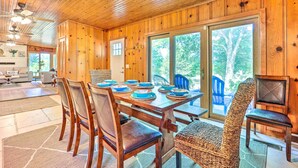 A wooden interior with a dining table set for six, surrounded by chairs, and a wicker chair in the foreground. - 'Lochview Lodge' Idyllic Farmhouse in Grove! (Grove)