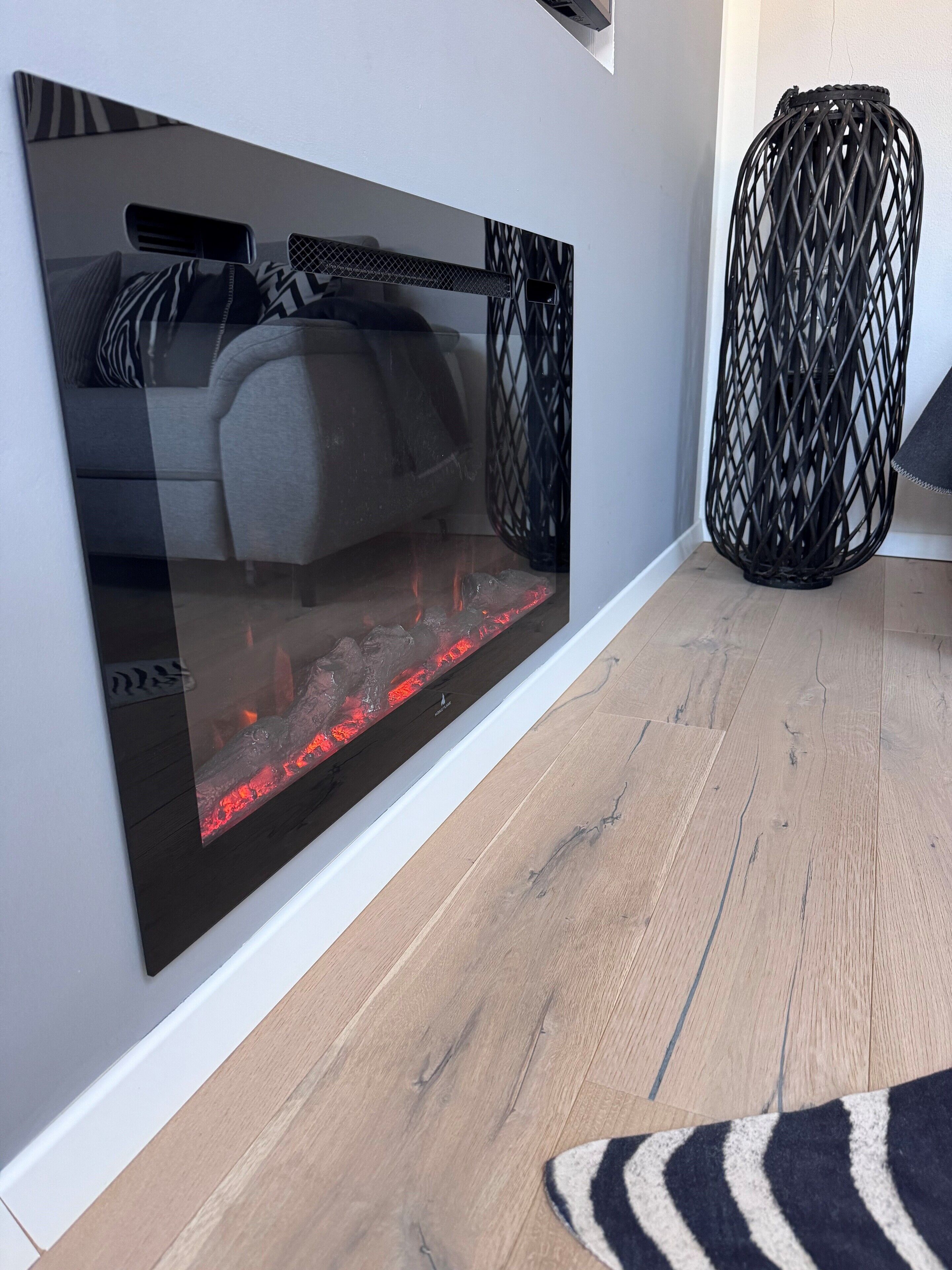 Ein modernes Wohnzimmer mit Kamin, einem grauen Sofa und einer schwarzen Webzimmerlampe.
