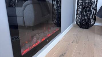 Ein modernes Wohnzimmer mit Kamin, einem grauen Sofa und einer schwarzen Webzimmerlampe.