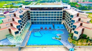 A hotel with a central swimming pool, multiple balconies, and a modern architectural design. - Muong Thanh Luxury Xuan Thanh Hotel (Tien Dien)