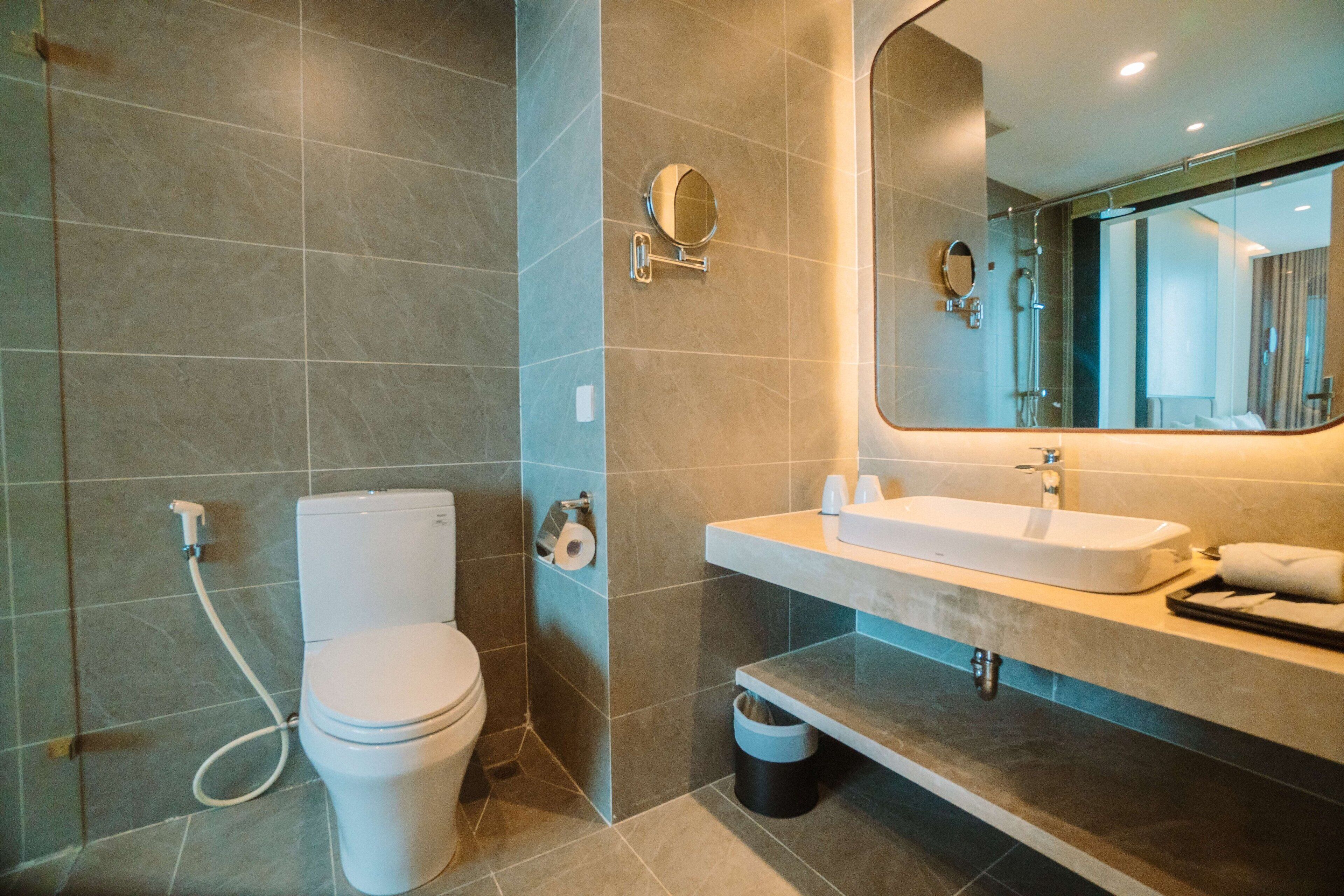 A modern bathroom with a toilet, sink, and mirror.