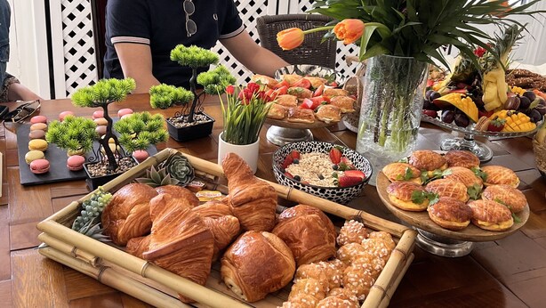 Una mesa con diversos pasteles, frutas y un bonsái decorativo.