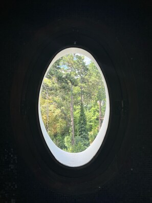 A round window with a view of dense green trees. - Domaine de Montmorency (Montmorency)