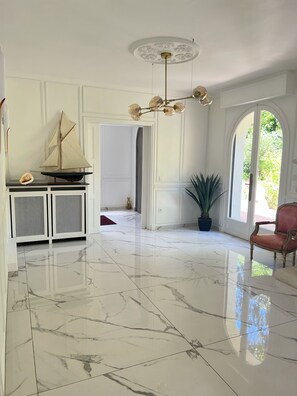 A spacious room with a polished marble floor, a decorative ceiling light, a model sailboat, and a potted plant. - Domaine de Montmorency (Montmorency)