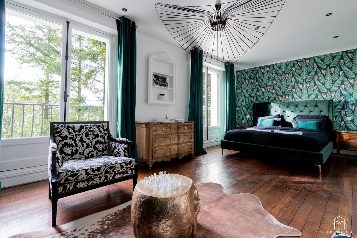 A bedroom with a large bed, a dresser, a chair, and a unique ceiling light.