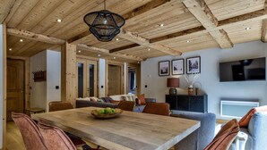 Un comedor con una mesa de madera, sillas acolchadas y una lámpara colgante.