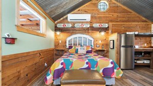 Une chambre confortable de style cabane, avec un lit, un banc et un coin cuisine.