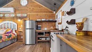 Une chambre confortable, aménagée dans le style d’un chalet, avec un lit, un réfrigérateur, une cuisinière et un évier.