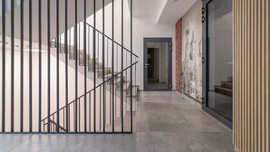 A modern interior with a staircase, a glass door, and a brick wall with a cityscape mural. - Stylish Studio in Krakow | Air Conditioning | Close to the Station (Kraków)