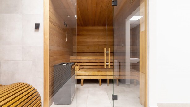 A modern sauna with a wooden interior, glass walls, and a bench. - Stylish Studio in Krakow | Air Conditioning | Close to the Station (Kraków)