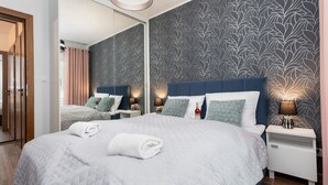 Een hotelkamer met een groot bed, twee nachtkastjes met lampen, een kledingkast en een spiegel.