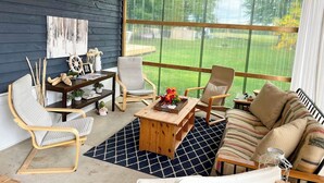 A cozy room with a dark wooden wall, a large window, a wooden coffee table, a striped sofa, and two chairs. - A Wave from it All, close to Lake Huron & Bayfield (Bayfield)
