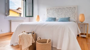 A bedroom with a large bed, two bedside lamps, and two woven baskets on the floor.