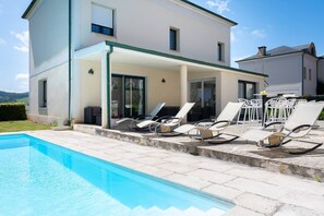 A two-story house with a swimming pool and outdoor seating.