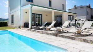 Una casa a due piani con un portico coperto e una piscina.