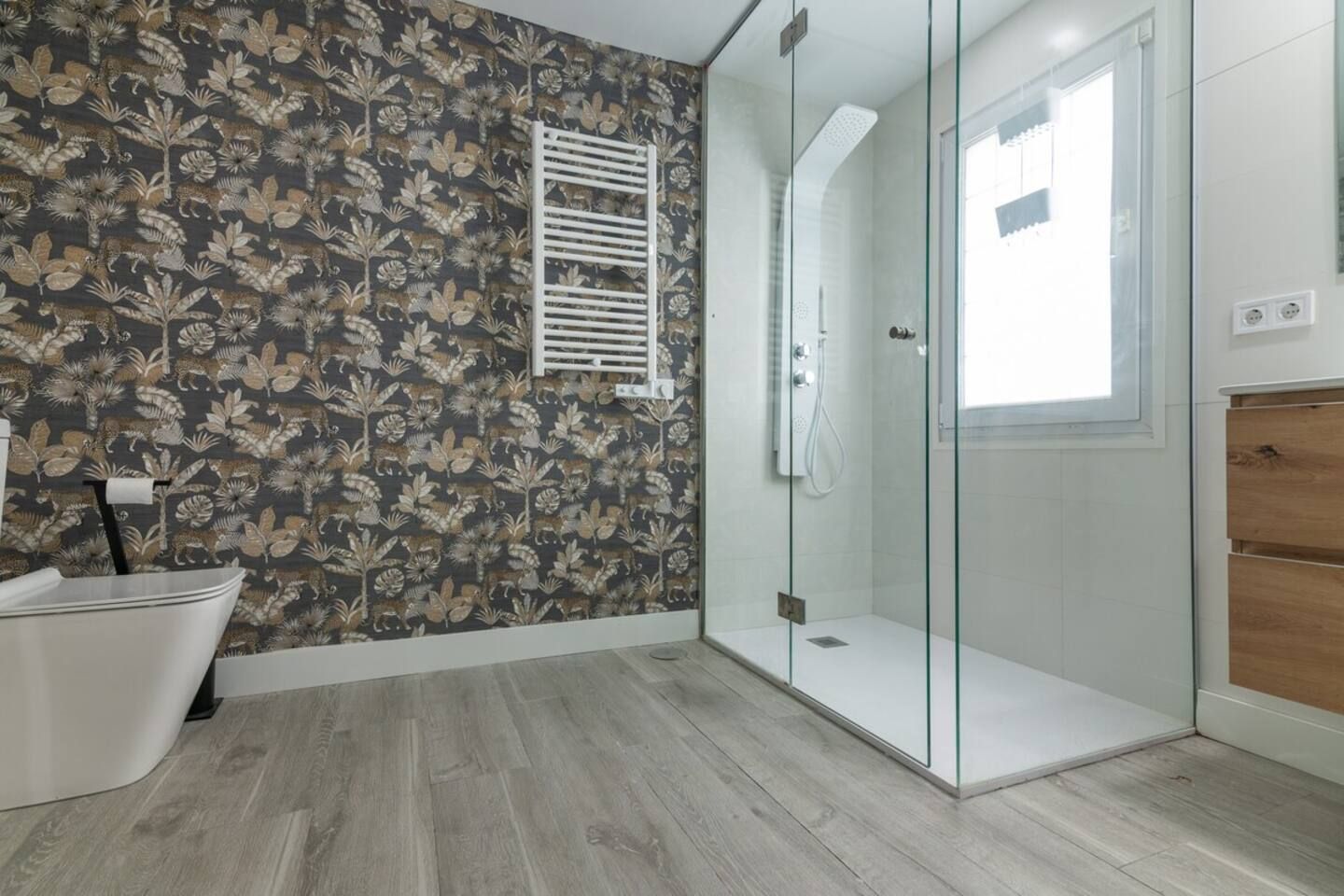 Un bagno con doccia, una vasca da bagno bianca e un rivestimento a motivi.