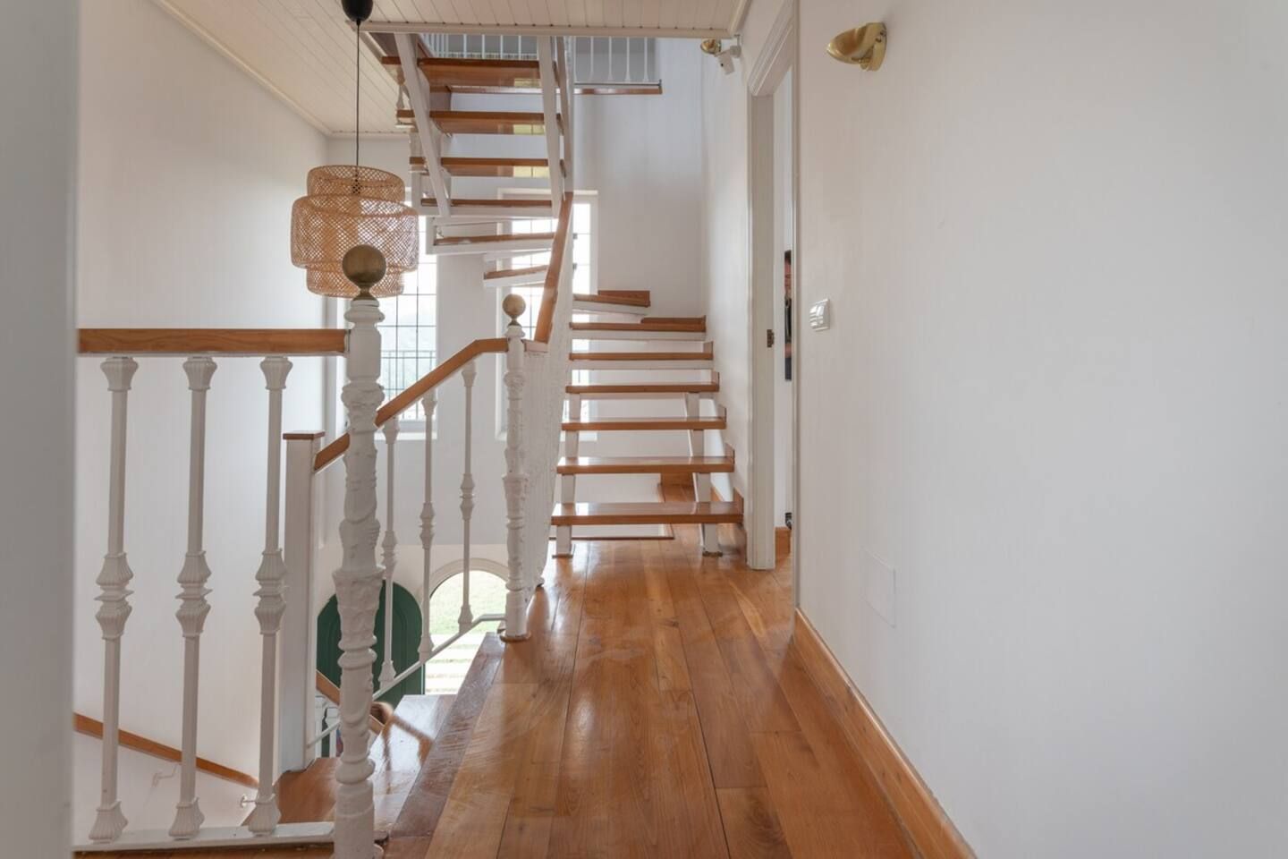 Un escalier avec des balustrades blanches et des marches en bois menant à l’étage supérieur.