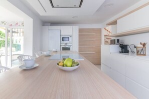 A modern kitchen with a central island, white cabinetry, and a dining area with a table and chairs.