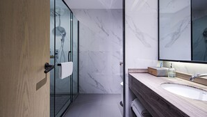Een moderne badkamer met een glazen douchecabine, een houten wastafelmeubel met een wastafel en een grote spiegel.