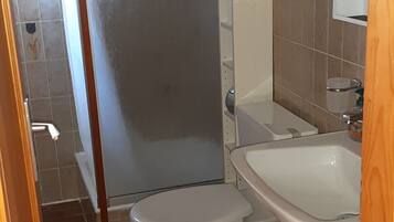 Une salle de bain équipée d’une douche, de toilettes, d’un lavabo et d’un meuble de rangement.