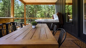 Una terraza de madera con una mesa, sillas, una planta en maceta y una parrilla.
