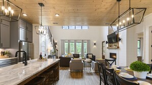 Una cocina amplia con encimera de mármol, un comedor con mesa y sillas de madera, y un espacio de sala de estar acogedor con sofá y chimenea.