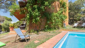 A swimming pool with a tiled edge, a lounge chair, and a potted plant.