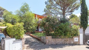 A residential property with a stone wall, a gated entrance, and a pathway leading to a house with a red roof.