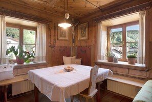 Une pièce en bois avec une table dressée pour deux personnes, un banc et une vue sur l’extérieur.