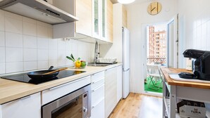 A modern kitchen with white cabinets, a stove, a refrigerator, and a dining area with a table and chairs. - Holiday Apartment Caracola with Balcony, Covered Terrace & Wi-Fi (Vinaròs)